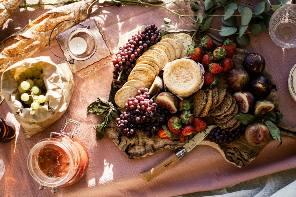 Elegant cheese platter with grapes, figs, and strawberries, perfect for a picnic.