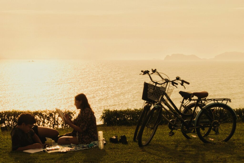 A couple enjoys a scenic picnic by the sea at sunset with bicycles in Lima, Peru.