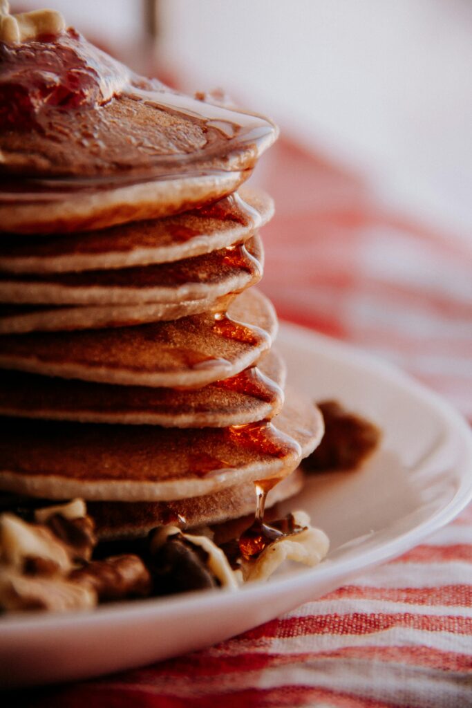 Delicious stack of pancakes drizzled with syrup and topped with nuts for breakfast.