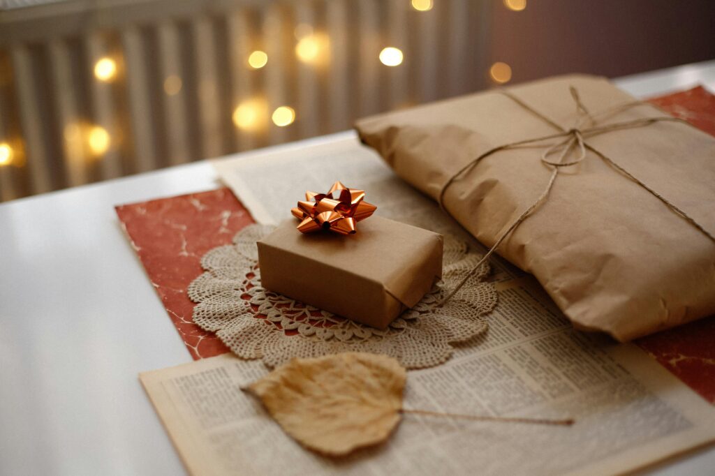 Warm autumn scene with gifts wrapped in brown paper and tied with twine, adorned with a red bow.